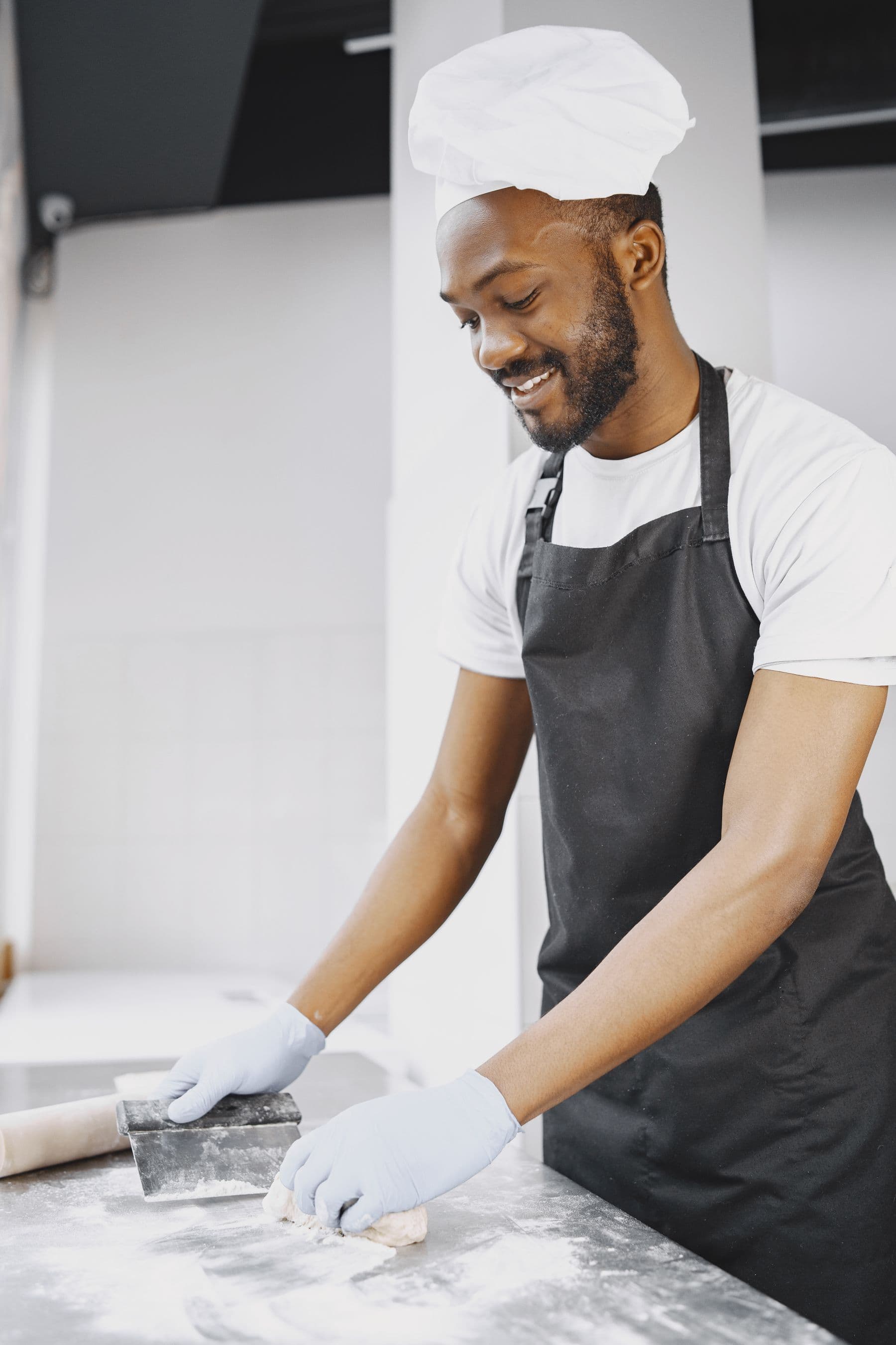 Smiling baker working dough in a professional kitchen